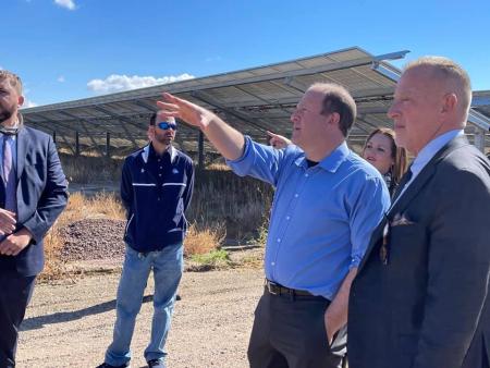 Governor Jared Polis with business people near solar panels